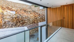 Een modern interieur met een stenen muur, glazen balustrade en houten lambrisering.