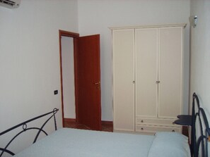 Une chambre à coucher comprenant un lit, une armoire et une porte donnant sur une autre pièce.