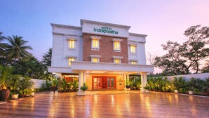 A hotel with a brick facade, a red entrance door, and a sign reading 'HOTEL Indraprastha.' - Hotel Indraprastha Pattazhy (Pathanapuram)