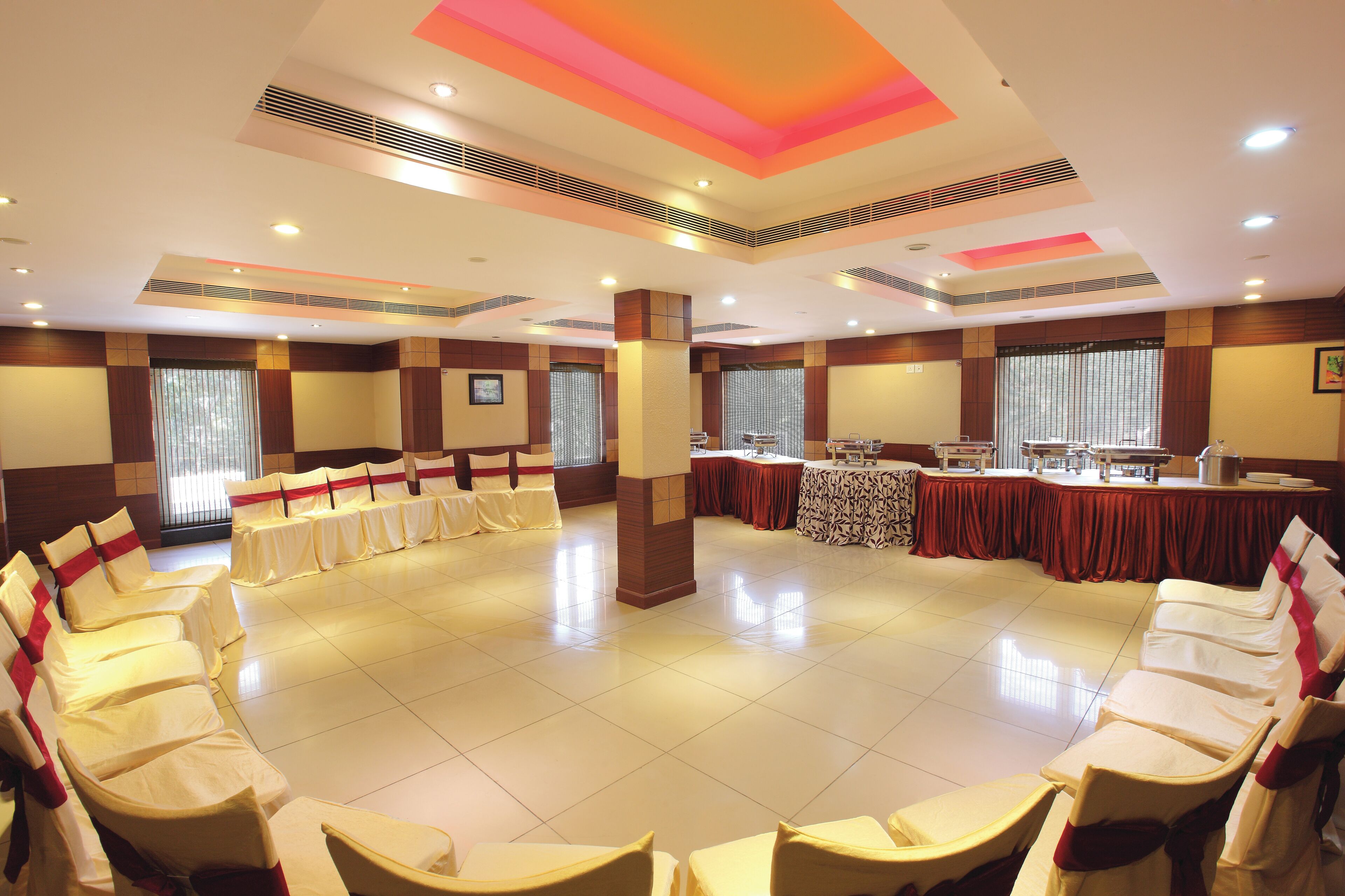 A conference room with rows of chairs, a long table, and a high ceiling with recessed lighting.