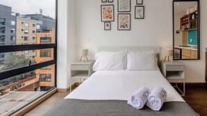Ein modernes Schlafzimmer mit einem großen Bett, zwei Nachttischen, einem Spiegel und Bildern an der Wand.