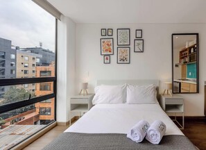 A modern hotel room with a large bed, two bedside tables, a mirror, and artwork on the wall. - NOK Modern 1BR Near Parque 93 Bogota (Bogotá)
