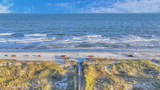 Una playa con una vía de tren, orilla de arena y océano.