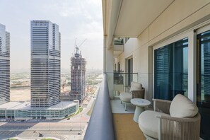 Ein Balkon mit Blick auf Hochhäuser, darunter eine Baustelle, und einer Sitzecke mit Tisch und Stühlen.