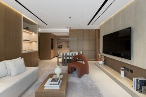 A modern living room with a sofa, coffee table, TV, and a dining area in the background. - Prime JLT Stay Near Metro Lakeside Dining (Dubai)