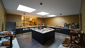 A breakfast buffet with a central island, a coffee station, and a television. - Unique Experience in Former Prison Cell (Alkmaar)
