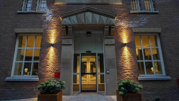 A brick building with a sign reading 'SCHUTTERSWEI' and a double door entrance. - Unique Experience in Former Prison Cell (Alkmaar)