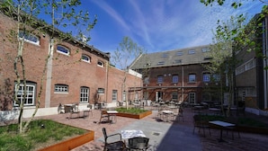 A courtyard with outdoor seating, brick buildings, and trees. - Unique Experience in Former Prison Cell (Alkmaar)