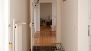 Ein Flur mit Heizkörper, Holzboden, schwarzem Fliesenbelag und einer weißen Decke mit einer besonderen Leuchte.