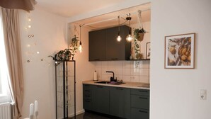 Una cocina moderna con gabinetes oscuros, encimera blanca y una lámpara colgante.