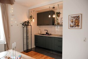A modern kitchen with dark cabinets, a white countertop, and a hanging light fixture.