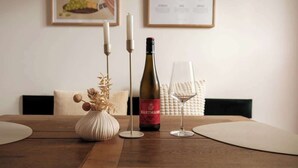 Una mesa de madera con una botella de vino, una copa y un jarrón con flores secas.