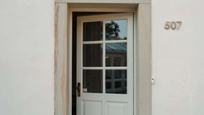 Eine weiße Tür mit Fensterglas, einer Messingklinke und einem kleinen Schild. An der Wand rechts neben der Tür ist die Nummer 507 zu sehen.