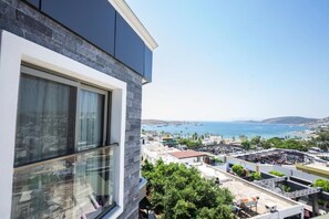 Un edificio moderno con un'ampia vetrata, vista su una zona costiera con imbarcazioni e un parcheggio.