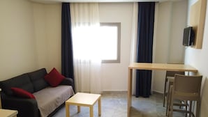 A living room with a sofa, a small table, a desk, and a chair. - m2 otel (Bodrum)