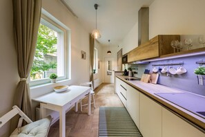 A modern kitchen with a dining area, wooden cabinets, and a window with curtains. - Exceptional Prague 1 Apt. in the City Center by Easybnb Premium (Prague)