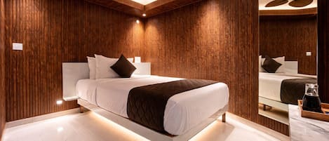 Un dormitorio moderno con una cama grande, paneles de madera, un ventilador de techo y un espejo.
