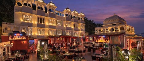 Un edificio de varios pisos con arquitectura tradicional, zona de estar al aire libre y un restaurante llamado 'Satin'.