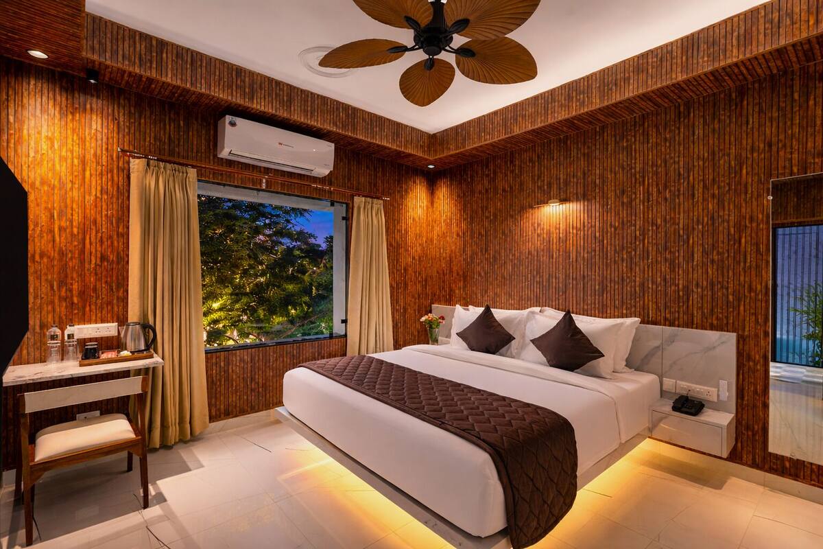 Un dormitorio moderno con paneles de madera en la pared, una cama grande con cabecera acolchada, un escritorio con silla y un equipo de aire acondicionado.