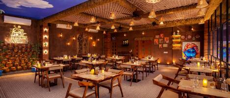 A restaurant with wooden tables and chairs, decorative lighting, and a mural on the wall.