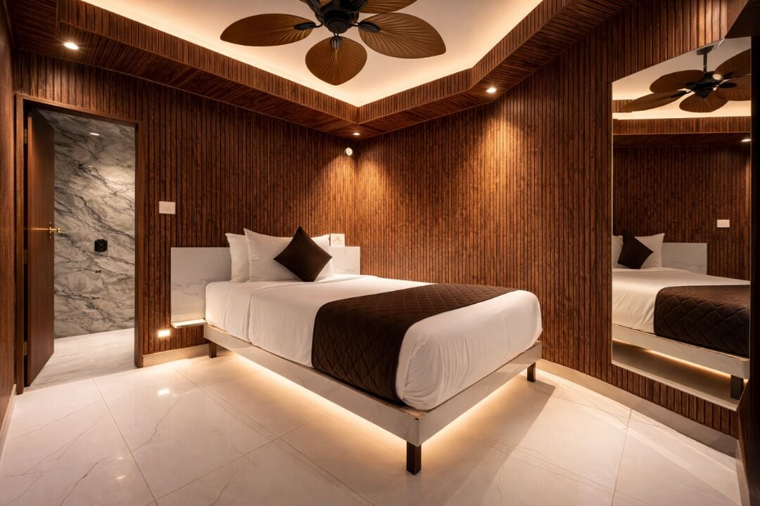 A modern bedroom with a large bed, wooden paneling, a marble wall, and a ceiling fan.