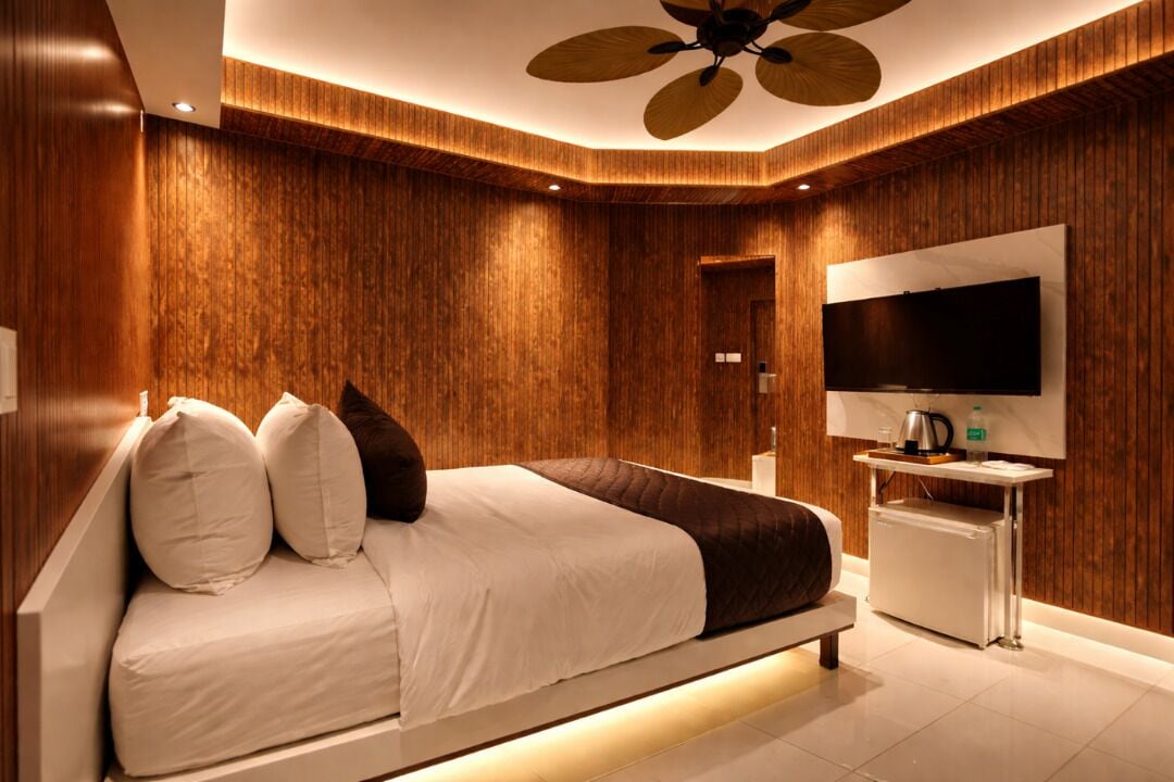 A modern bedroom with a large bed, a TV, and a ceiling fan.