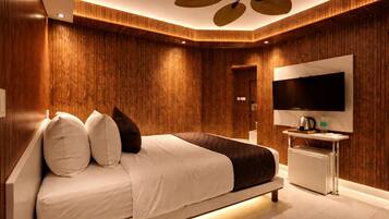 A modern bedroom with a large bed, a TV, and a ceiling fan.