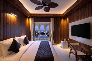 Habitación de hotel con una cama grande, televisión, ventilador de techo y vistas a la ciudad.