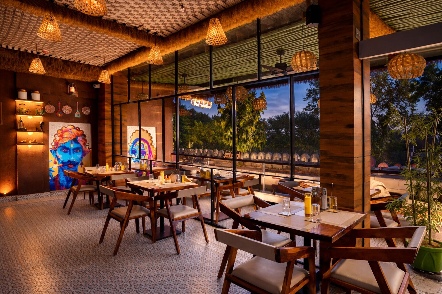 Een restaurant met houten tafels en stoelen, grote ramen en hangende lampen.