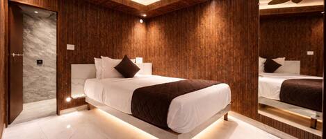 A modern bedroom with a large bed, wooden paneling, a ceiling fan, and a marble floor.