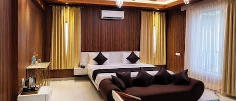 A hotel room with a bed, a sofa, a coffee table, a desk, and a ceiling fan.