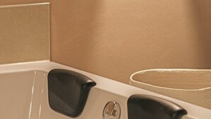 Una vasca da bagno con due maniglie nere e uno scarico circolare.