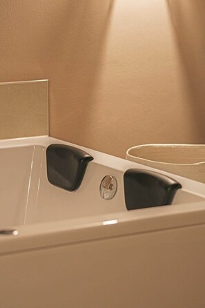 A bathtub with two black handles and a circular drain.