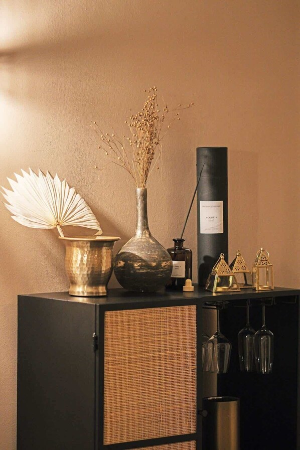 A black cabinet with a woven basket, a vase with dried flowers, a decorative fan, and a tall black bottle.
