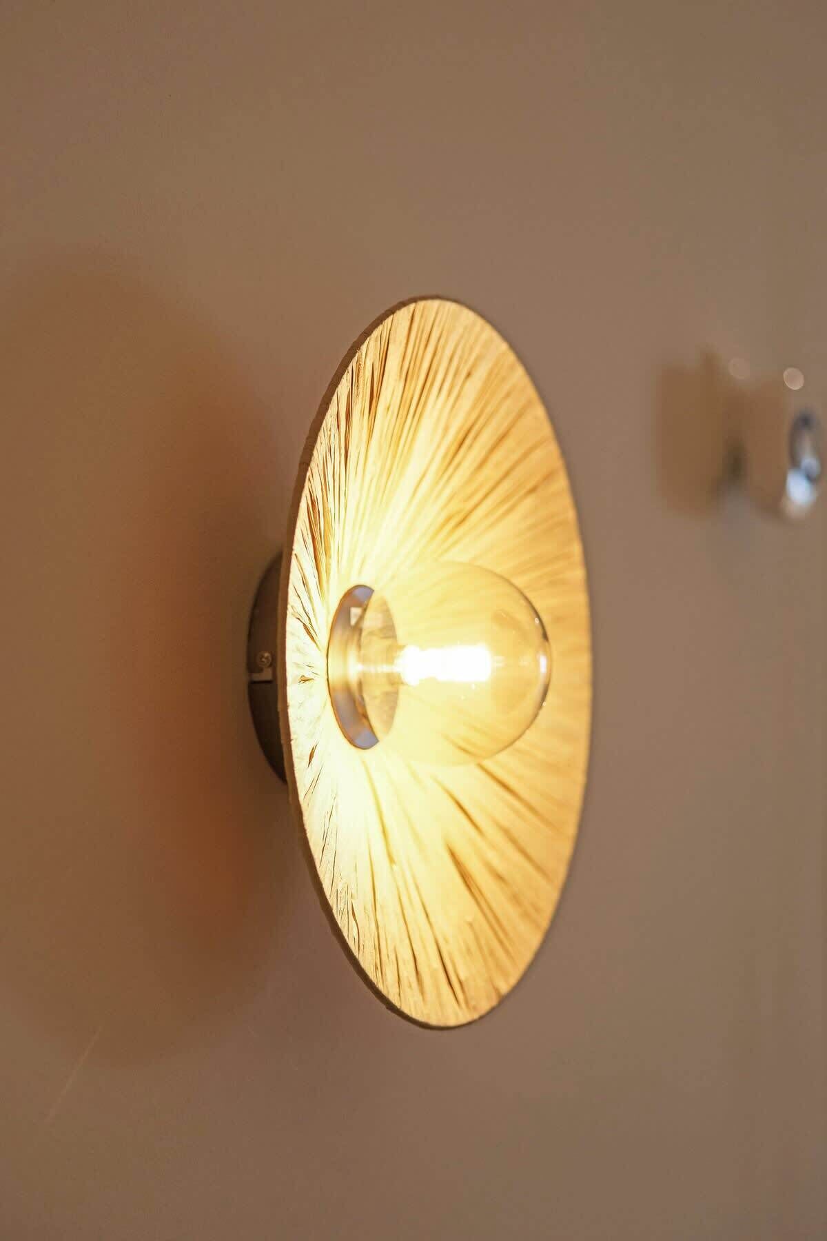 Eine wandmontierte Leuchte mit kreisförmigem Design und einer zentralen Glühbirne.