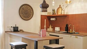 Eine Küche mit einer Holzinsel, zwei Barhocker, Pendelleuchten, einem dekorativen Teller und einem Schild.