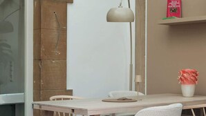 Un comedor con una mesa, sillas, una lámpara y un libro en una estantería.