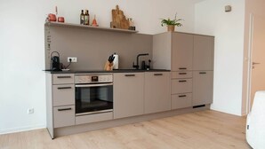Una cocina moderna con horno integrado, un lavamanos y una encimera con cafetera.