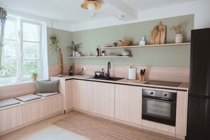Une cuisine moderne dotée d’un four encastré, d’un évier et d’une fenêtre donnant sur un espace verdoyant.