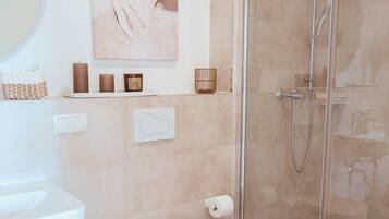 Een moderne badkamer met toilet, bidet en douchecabine met glazen wanden.