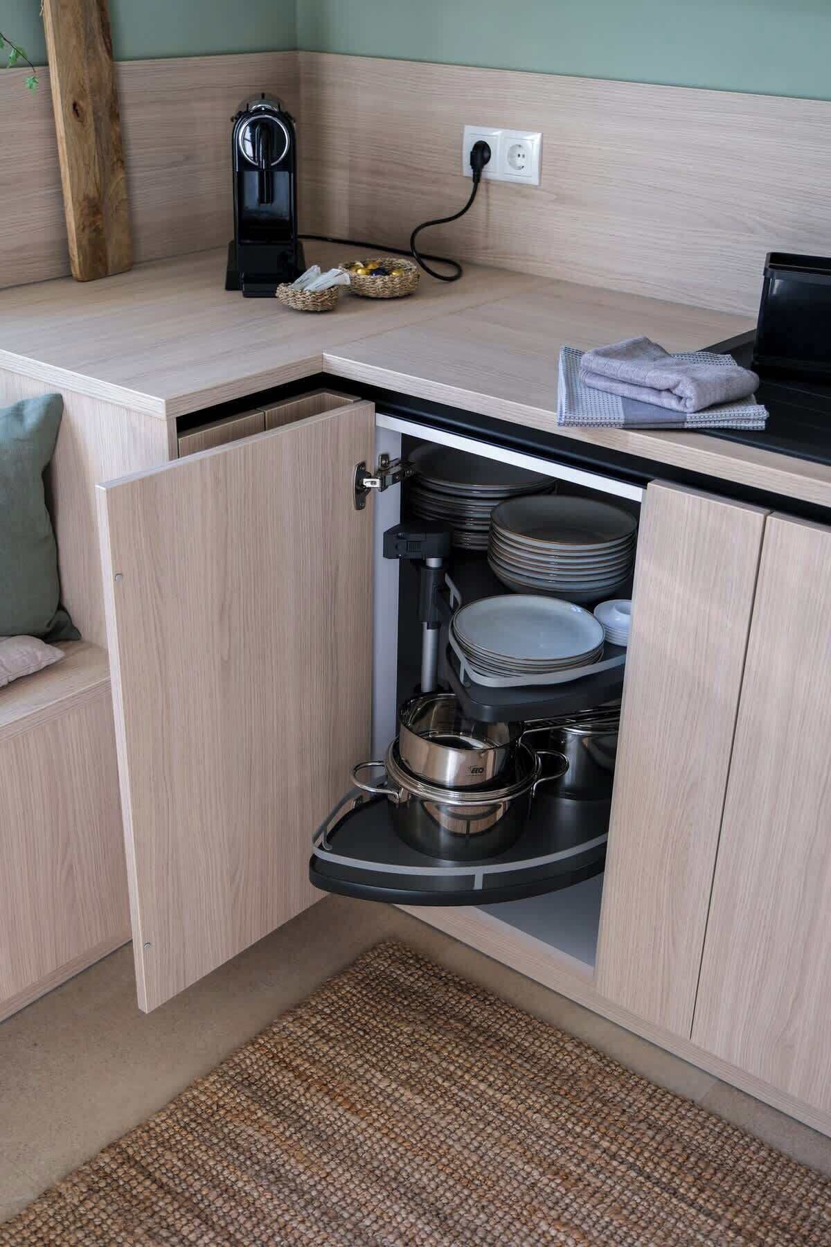 A kitchen with a built-in cabinet, a coffee maker, and stacked plates.