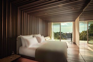 Une chambre moderne avec un grand lit, un plafond en bois à lattes et un balcon offrant une vue sur la mer.
