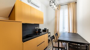 A compact kitchen with yellow cabinets, a black countertop, and a dining table with chairs. - Ortigia in Giallo by Wonderful Italy (Siracusa)