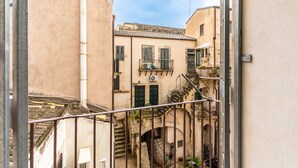 A narrow alleyway with buildings on either side, a staircase, and a metal railing. - Ortigia in Giallo by Wonderful Italy (Siracusa)