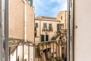 A narrow alleyway with buildings on either side, a staircase, and a metal railing. - Ortigia in Giallo by Wonderful Italy (Siracusa)