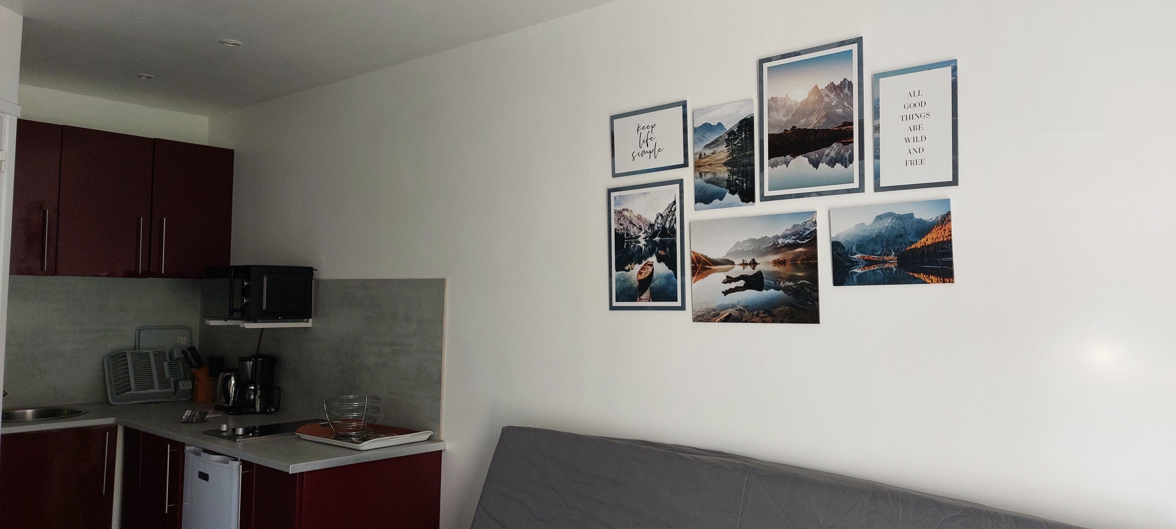 Eine Küche mit Mikrowelle, Kaffeemaschine und Spüle. An der Wand befinden sich gerahmte Bilder.