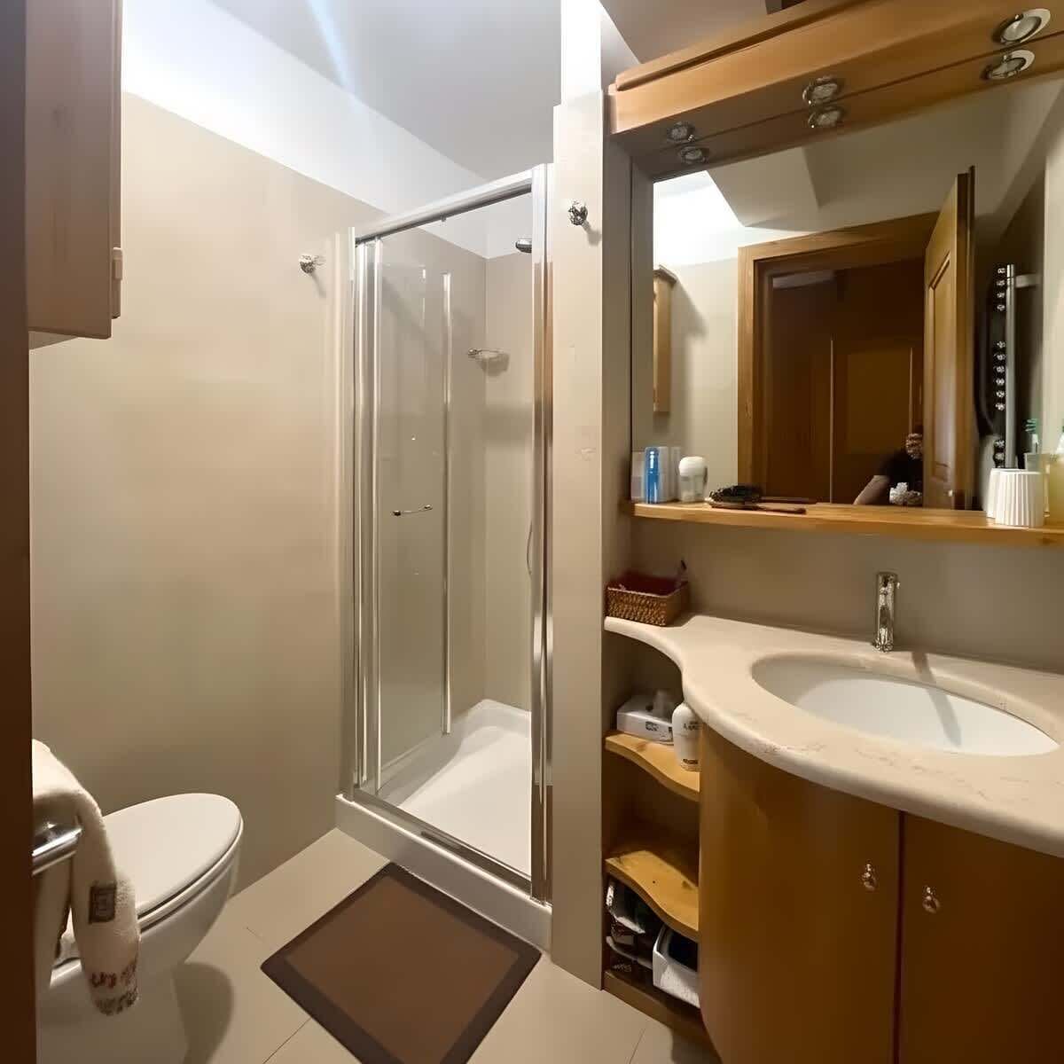 Ein Badezimmer mit Dusche, Toilette, Waschbecken und Spiegel.