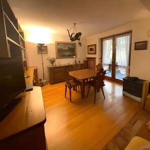 Una sala de estar con una mesa de comedor de madera, sillas, un televisor y una chimenea.