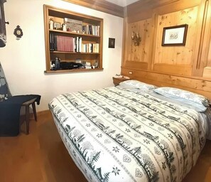 A bedroom with a bed, a wooden headboard, a bookshelf, and a desk. - Casa Verocai Classic Retreat in Cortina (Cortina d'Ampezzo)
