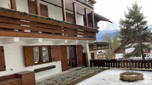 A building with wooden balconies, a stone pathway, and a snow-covered ground. - Casa Verocai Classic Retreat in Cortina (Cortina d'Ampezzo)